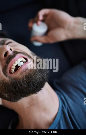 uomo emotivo depresso con barba che prende pillole durante l'episodio depressivo, consapevolezza della salute mentale Foto Stock