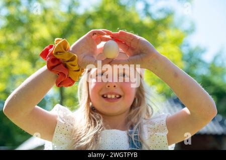 La giovane ragazza felice ha raccolto un uovo fresco dai polli Foto Stock