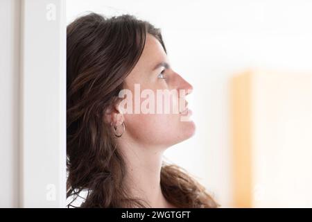 Giovane donna seduta a casa, vista profilo Foto Stock