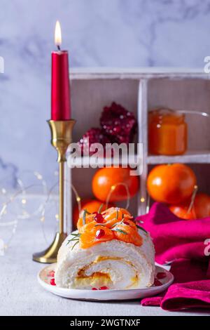 Rotolo di meringa ripieno di mascarpone, crema e marmellata di mandarini, decorato con mandarini e semi di melograno. Foto Stock