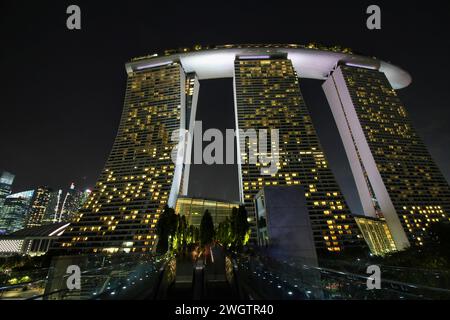 Le triple torri dell'hotel Marina Bay Sands sono completamente illuminate e si innalzano maestosamente contro il cielo notturno evidenziando lo skyline di Singapore Foto Stock