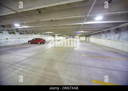Auto rossa solitaria nel garage coperto vuoto di notte Foto Stock