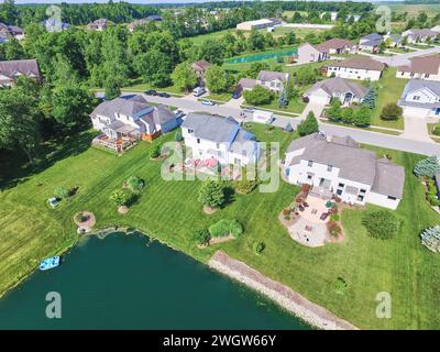 Veduta aerea delle residenze suburbane sul lago con prati curati Foto Stock