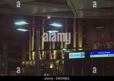 Bruxelles, Belgio. 5 febbraio 2024. Lampione di forma insolita con una luce brillante. Iscrizioni illuminate. Roger. Facciata dell'edificio di notte Foto Stock