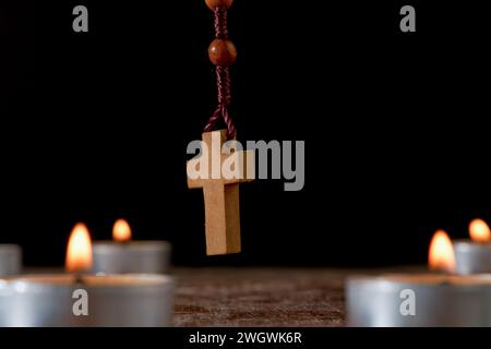 Cerchio di candele accese con un rosario di legno perline di preghiera al centro e un incenso smolante sullo sfondo isolato su sfondo nero Foto Stock