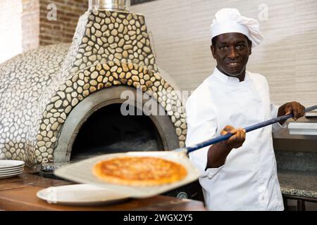 Ritratto di chef felice preparazione pizza fuori dal forno in cucina Foto Stock