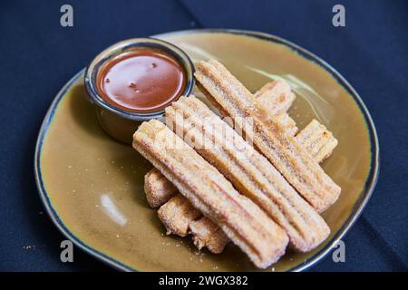 Churros con salsa da immersione su piatto artigianale, vista ravvicinata Foto Stock