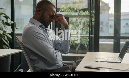 Esaurito malato anziano uomo d'affari anziano stanco Africano americano etnia ufficio lavoro esecutivo sul computer tipizzazione sentire mal di testa dolore oculare Foto Stock
