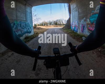 Pedalare su una strada di ghiaia tra alberi in una foresta Foto Stock