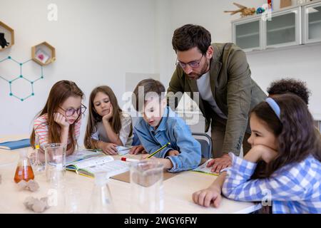 Insegnante di uomo con bambini durante la lezione di chimica in classe scolastica. Foto Stock