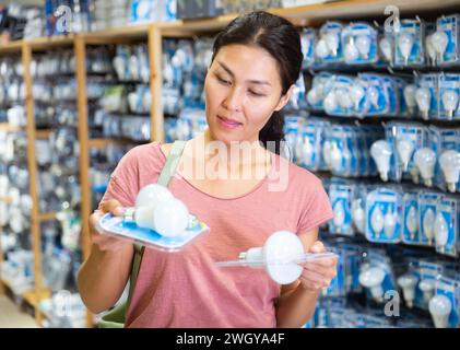 La donna ha scelto la lampada a risparmio energetico presso il negozio di hardware Foto Stock