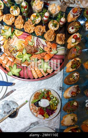 Un'incredibile esposizione di sushi e tartine sontuosi su un tavolo di vetro, caratterizzato da piatti di pesce preparati ad arte e condimenti colorati, che creano una festa per te Foto Stock