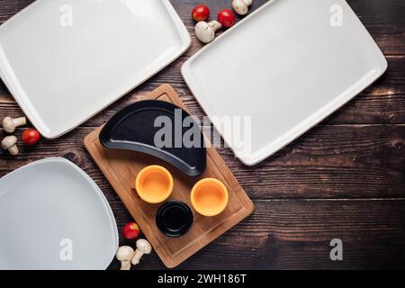 Vista dall'alto dei piatti vuoti con verdure intorno a loro su un tavolo di legno Foto Stock