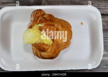 Crema di pasticceria su una pasticceria danese ripiena di crema di formaggio dolce e sciroppo dolce, impasto dolce da forno cotto nel forno con farina, zucchero e. Foto Stock