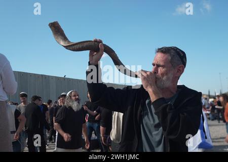 Un manifestante religioso ebreo fa saltare la Shofar mentre i manifestanti israeliani di destra ballano bloccando i camion egiziani che trasportano aiuti umanitari nella Striscia di Gaza sul lato israeliano dell'attraversamento di Karem Abu Salem, noto anche come attraversamento di Kerem Shalom il 6 febbraio 2024 a Kerem Shalom, Israele. Da diversi giorni ormai, i coloni israeliani bloccano i camion che trasportano rifornimenti umanitari ai palestinesi nella Striscia di Gaza assediata. Foto Stock