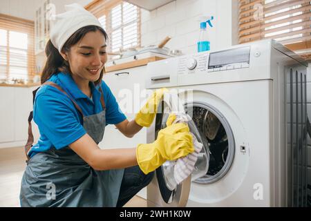 Casalinga mano in guanto protettivo pulisce e salvietta lavatrice. Evidenziando i normali lavori domestici Foto Stock