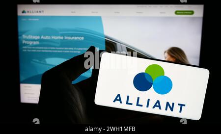 Persona che detiene lo smartphone con il logo dell'istituto finanziario statunitense Alliant Credit Union davanti al sito Web. Mettere a fuoco il display del telefono. Foto Stock