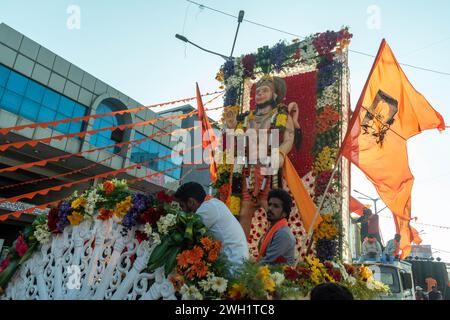 Hassan, Karnataka, India - 10 gennaio 2023: Un gruppo di devoti pregano e adornano una colorata statua di Hanuman con ghirlande durante un vivace re Foto Stock