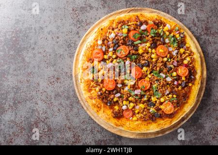 Pizza speziata con Taco messicano con carne macinata, pomodori, mais, fagioli neri, formaggio cheddar, cipolla rossa sulla tavola di legno sul tavolo. Via superiore orizzontale Foto Stock