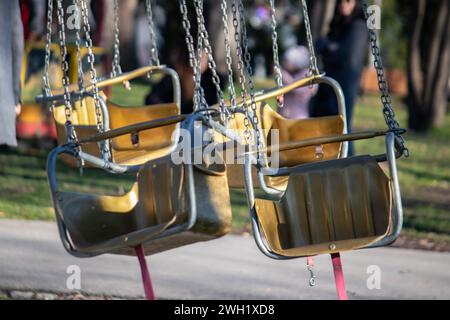 Seggiolino in metallo a giostra vuoto nel concetto di parco divertimenti in un parco cittadino di Belgrado, in una bella giornata di sole nel fine settimana. Foto Stock