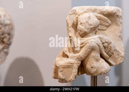 Primo piano su un pezzo di antica scultura scolpita in pietra che rappresenta un piccolo angelo Foto Stock