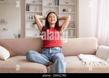 Giovane donna asiatica sorridente che si gode un momento di relax a casa Foto Stock