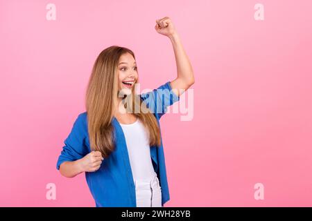 Foto di una ragazza fortunata che indossa camicia blu braccia guance pugni che urlano sì sembra uno spazio vuoto sfondo di colore rosa isolato Foto Stock