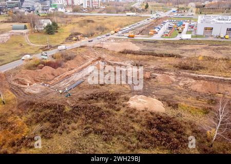 Fotografia con drone di fognature che vengono girate giù in un fosso vicino a una strada durante la giornata nuvolosa autunnale Foto Stock