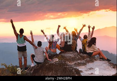 Un grande gruppo di giovani amici felici gode di un tramonto colorato sulla cima della montagna Foto Stock