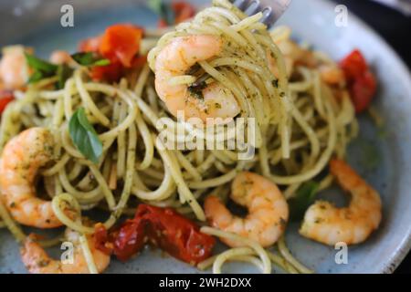 Spaghetti con pesto, pomodori confit e gamberi grigliati. Foto Stock