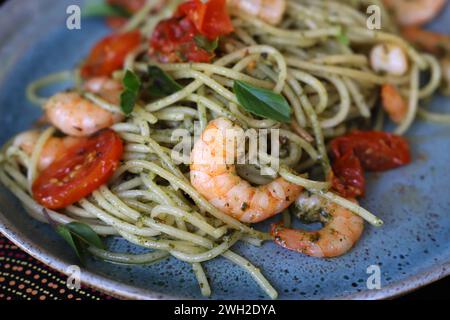 Spaghetti con pesto, pomodori confit e gamberi grigliati. Foto Stock