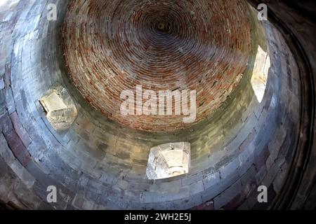 Tetto di un'antica chiesa in pietra con piccole finestre e raggi di luce. Foto Stock