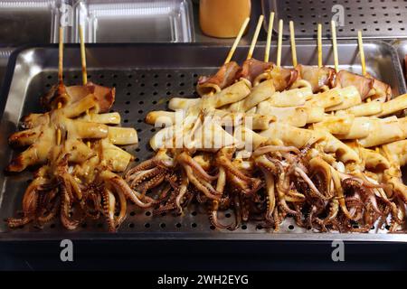 Mercato alimentare notturno di Taiwan - mercato notturno di Raohe a Taipei. Calamari e polpo al barbecue sul bastoncino. Foto Stock