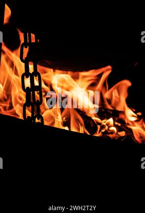 Cucinare su un calderone sul fuoco. Fiamme di fuoco al buio. Foto Stock