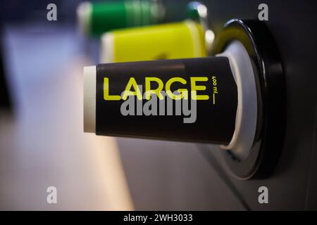 Caffetteria, negozio, caffetteria. Tazze di carta colorata, nere grandi, gialle medie, verdi piccole dimensioni diverse per bevande calde caffè, tè da portare Foto Stock