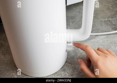 Include un bollitore elettrico per bollire l'acqua. Concetto di risparmio energetico, elettricità costosa. Foto Stock