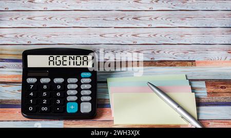 Simbolo dell'agenda. Calcolatrice con la parola Agenda Concept su uno sfondo bellissimo con adesivi e una penna. Foto Stock