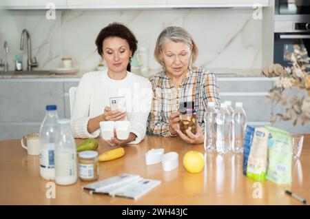 Due donne che scansionano prodotti diversi utilizzando il proprio smartphone Foto Stock