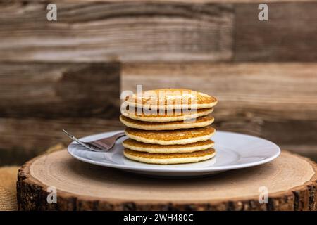 Una grande pila di frittelle con una forchetta contro un fondo di legno semplice senza sciroppo Foto Stock