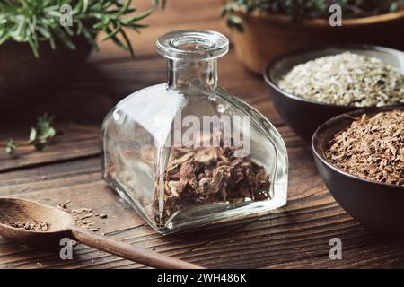 Bottiglia di corteccia medicinale secca ed erbe per fare infusione o tintura curativa. Ciotole di piante medicinali essiccate e mortaio di legno di fresca guarigione Foto Stock
