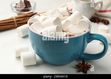 Gustosa cioccolata calda con marshmallow e ingredienti su tavola bianca, primo piano Foto Stock