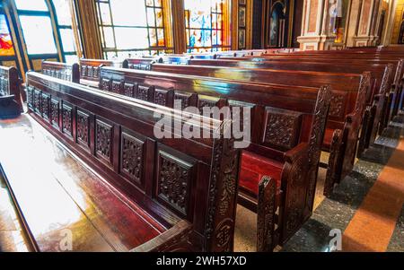 Panchine vuote in legno di una chiesa cristiana. Alterazione sfocata sullo sfondo. Messa a fuoco selettiva. Concetto di servizio religioso o chiese vuote. Righe Foto Stock