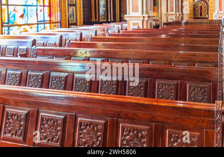 Panchine vuote in legno di una chiesa cristiana. Alterazione sfocata sullo sfondo. Messa a fuoco selettiva. Concetto di servizio religioso o chiese vuote. Righe Foto Stock