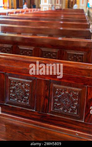 Panchine vuote in legno di una chiesa cristiana. Alterazione sfocata sullo sfondo. Messa a fuoco selettiva. Concetto di servizio religioso o chiese vuote. Righe Foto Stock