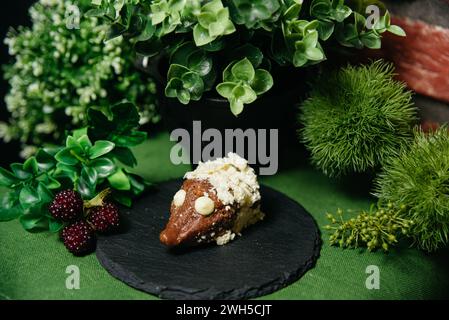 Un creativo dessert a forma di riccio fatto di biscotti, latte condensato e cacao in polvere, decorato con gocce di cioccolato bianco su un piatto di ardesia Foto Stock