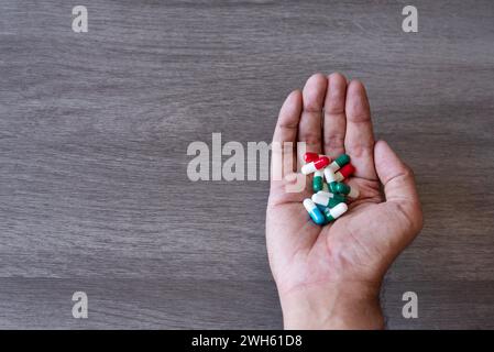 Mano che tiene una pila di pillole colorate. Copia spazio per il testo. Abuso di droga, concetto di dipendenza. Foto Stock