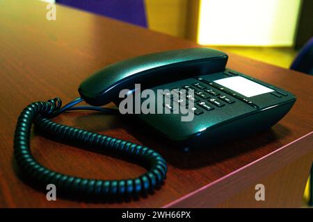 Un elegante telefono nero e la sua cornetta poggiano su una scrivania, incorporando la moderna tecnologia di comunicazione in un moderno spazio di lavoro. Foto Stock