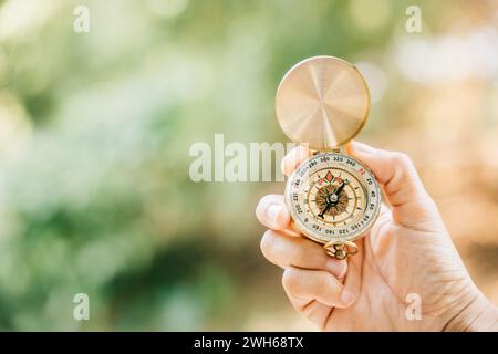 Nel mezzo di una foresta serena e sul lato di un lago tranquillo, una donna tiene in mano una bussola Foto Stock