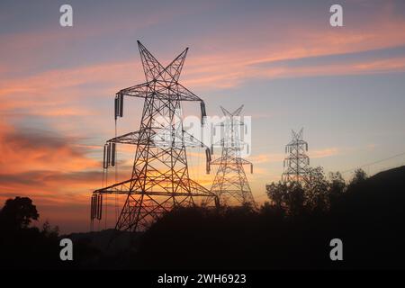 una torre di linea elettrica con tramonto sullo sfondo Foto Stock