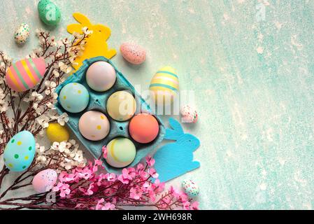 Buona Pasqua. Vista dall'alto delle uova dipinte di pasqua in una scatola di cartone blu e fiori di mandorle su sfondo blu Foto Stock